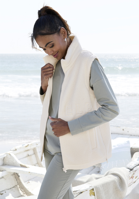 Bild: Fleeceweste von Elbsand: Fleeceweste aus Teddyplüsch von Elbsand. Mit hohem Kragen. Schriftzug-Stickerei vorn und hinten. Reißverschlüsse seitlich am Saum. Eingrifftaschen vorn. Weiche Fleece-Qualität.