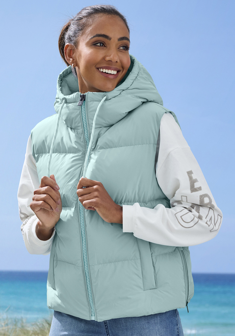 Bild: Steppweste von Elbsand: Unifarbene Steppweste von Elbsand. Hoher Stehkragen und Kapuze mit kontrastfarbenem Tunnelzug zum individuellen Verstellen der Weite. Reißverschluss vorn und zusätzliche Reißverschlüsse an beiden Seiten. Zwei Eingrifftaschen. Tonaler Logodruck am Rücken. Schöner Begleiter für kühleres Wetter. Angenehmes Material.