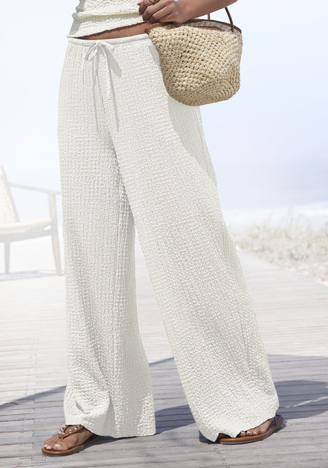 Bild: Schlupfhose von LASCANA: <h3>Bequeme Schlupfhose von <strong>LASCANA</strong></h3>
<p>
Die Schlupfhose von <strong>LASCANA</strong> vereint Komfort und Stil auf perfekte Weise. Ihr Gummizugbund mit Kordelzug sorgt für eine individuelle Passform und maximalen Tragekomfort. Praktische Seitennahttaschen bieten nicht nur Platz für kleine Essentials, sondern fügen sich auch harmonisch ins Gesamtbild ein. Dank der modischen Strukturware, die bügelfrei ist, bleibt die Hose auch bei längerem Tragen stets gepflegt und elegant.
</p>

<h4>Details und Mehrwerte der Schlupfhose</h4>
<p>
Diese Hose überzeugt durch ihre figurumspielende Passform und die gerade, weite Beinform, die für eine lässige Silhouette sorgt. Die unifarbene Optik lässt sich vielseitig kombinieren und verleiht jedem Outfit eine moderne Note. Maschinenwäsche macht die Pflege unkompliziert und zeitsparend, sodass die Schlupfhose schnell wieder einsatzbereit ist. Perfekt für den Alltag, ohne auf Stil verzichten zu müssen.
</p>

<h4>Kombinationsmöglichkeiten und Trageanlässe</h4>
<p>
Die Schlupfhose von <strong>LASCANA</strong> ist der ideale Begleiter für zahlreiche Anlässe. Sie lässt sich hervorragend mit einem lässigen T-Shirt oder einer schicken Bluse kombinieren, perfekt für entspannte Tage in der Stadt oder beim Treffen mit Freunden. Sneakers runden den Streetwear-Look ab, während elegante Sandalen für ein schickes Abendoutfit sorgen. Ob beim Workout, beim Relaxen zu Hause oder bei Outdoor-Aktivitäten – die Hose bietet den gewünschten Komfort und Bewegungsfreiheit.
</p>
<p>
Mit der Schlupfhose von <strong>LASCANA</strong> verschmelzen Stil und Komfort in perfekter Harmonie!
</p>