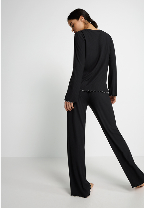 Bild: Pyjama von LSCN by LASCANA: Relaxen mit Style – der Pyjama von LSCN by Lascana ist die perfekte Kombination aus Komfort und trendigen Details. Das Langarmshirt mit Rundhalsausschnitt und legerem Fit sorgt für ein entspanntes Tragegefühl, das dich durch den ganzen Tag begleitet – oder eben durch die ganze Nacht. Die Hose mit elastischem Bund und Tunnelzug passt sich deinem Körper an und garantiert dabei maximalen Komfort. Die weiche Rippware umhüllt dich sanft, während die Kontrast-Kräsuselkanten dem Set das gewisse Etwas verleihen. Ein Set, das nicht nur bequem ist, sondern auch mit modernen Details überzeugt – der Pyjama von LSCN by Lascana.