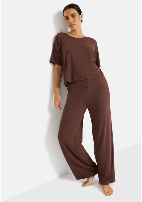 Bild: Pyjama von LSCN by LASCANA: Schlaf gut, träum schön! In diesem Pyjama von LSCN by Lascana wird Relaxen zum Style-Statement. Das locker geschnittene Shirt mit Rundhalsausschnitt, kurzen Ärmeln und überschnittenen Schultern bietet maximale Bewegungsfreiheit und einen entspannten Fit. Die passende Hose mit bequemem Gummizug sitzt angenehm an der Taille und punktet mit einem angedeuteten Eingriff samt Knopfleiste, ein lässiges Detail mit klassischem Touch. Das gerade geschnittene Bein rundet den Look ab und macht das Loungeset zur perfekten Mischung aus Komfort und Coolness. Mach die Nacht zu deinem Cozy-Moment – mit dem Pyjama von LSCN by Lascana.
