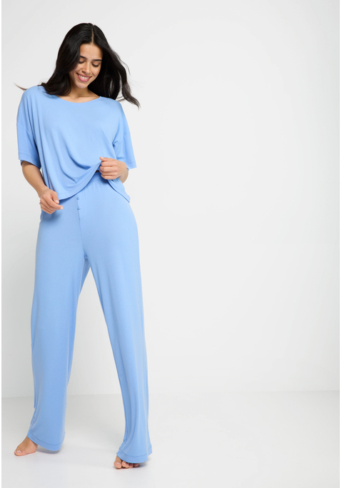Bild: Pyjama von LSCN by LASCANA: Schlaf gut, träum schön! In diesem Pyjama von LSCN by Lascana wird Relaxen zum Style-Statement. Das locker geschnittene Shirt mit Rundhalsausschnitt, kurzen Ärmeln und überschnittenen Schultern bietet maximale Bewegungsfreiheit und einen entspannten Fit. Die passende Hose mit bequemem Gummizug sitzt angenehm an der Taille und punktet mit einem angedeuteten Eingriff samt Knopfleiste, ein lässiges Detail mit klassischem Touch. Das gerade geschnittene Bein rundet den Look ab und macht das Loungeset zur perfekten Mischung aus Komfort und Coolness. Mach die Nacht zu deinem Cozy-Moment – mit dem Pyjama von LSCN by Lascana.