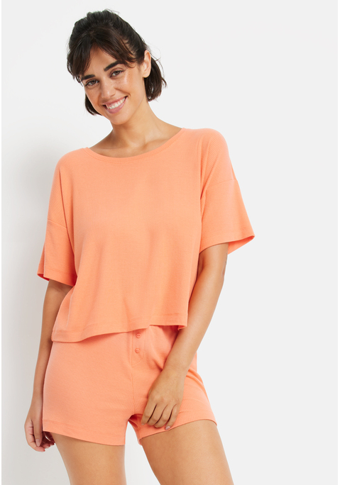 Bild: Shorty von LSCN by LASCANA: Lässiger Look, maximaler Komfort: Der Shorty von LSCN by Lascana bringt dich in den perfekten Chill-Modus. Das kurze, leger geschnittene Halbarmshirt mit überschnittenen Schultern bietet dir eine entspannte Passform, die dich nicht nur nachts, sondern auch beim Relaxen zu Hause begleitet. Die Shorts mit geradem Bein und einer kurzen Zier-Knopfleiste setzen ein süßes Detail und sorgen für einen coolen Look. Die weiche, elastische Rippqualität fühlt sich richtig angenehm auf der Haut an. Dadurch ist der Pyjama perfekt für gemütliche Abende. Kuschel dich ein und genieße den Komfort – mit dem Shorty von LSCN by Lascana.
