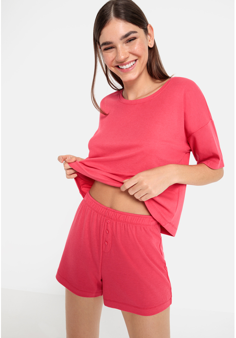 Bild: Shorty von LSCN by LASCANA: Lässiger Look, maximaler Komfort: Der Shorty von LSCN by Lascana bringt dich in den perfekten Chill-Modus. Das kurze, leger geschnittene Halbarmshirt mit überschnittenen Schultern bietet dir eine entspannte Passform, die dich nicht nur nachts, sondern auch beim Relaxen zu Hause begleitet. Die Shorts mit geradem Bein und einer kurzen Zier-Knopfleiste setzen ein süßes Detail und sorgen für einen coolen Look. Die weiche, elastische Rippqualität fühlt sich richtig angenehm auf der Haut an. Dadurch ist der Pyjama perfekt für gemütliche Abende. Kuschel dich ein und genieße den Komfort – mit dem Shorty von LSCN by Lascana.