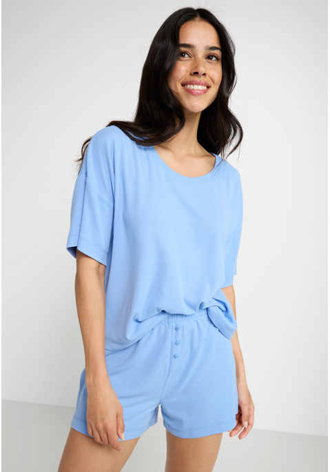 Bild: Shorty von LSCN by LASCANA: Lässiger Look, maximaler Komfort: Der Shorty von LSCN by Lascana bringt dich in den perfekten Chill-Modus. Das kurze, leger geschnittene Halbarmshirt mit überschnittenen Schultern bietet dir eine entspannte Passform, die dich nicht nur nachts, sondern auch beim Relaxen zu Hause begleitet. Die Shorts mit geradem Bein und einer kurzen Zier-Knopfleiste setzen ein süßes Detail und sorgen für einen coolen Look. Die weiche, elastische Rippqualität fühlt sich richtig angenehm auf der Haut an. Dadurch ist der Pyjama perfekt für gemütliche Abende. Kuschel dich ein und genieße den Komfort – mit dem Shorty von LSCN by Lascana.