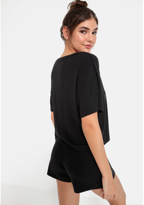 Bild: Shorty von LSCN by LASCANA: Lässiger Look, maximaler Komfort: Der Shorty von LSCN by Lascana bringt dich in den perfekten Chill-Modus. Das kurze, leger geschnittene Halbarmshirt mit überschnittenen Schultern bietet dir eine entspannte Passform, die dich nicht nur nachts, sondern auch beim Relaxen zu Hause begleitet. Die Shorts mit geradem Bein und einer kurzen Zier-Knopfleiste setzen ein süßes Detail und sorgen für einen coolen Look. Die weiche, elastische Rippqualität fühlt sich richtig angenehm auf der Haut an. Dadurch ist der Pyjama perfekt für gemütliche Abende. Kuschel dich ein und genieße den Komfort – mit dem Shorty von LSCN by Lascana.